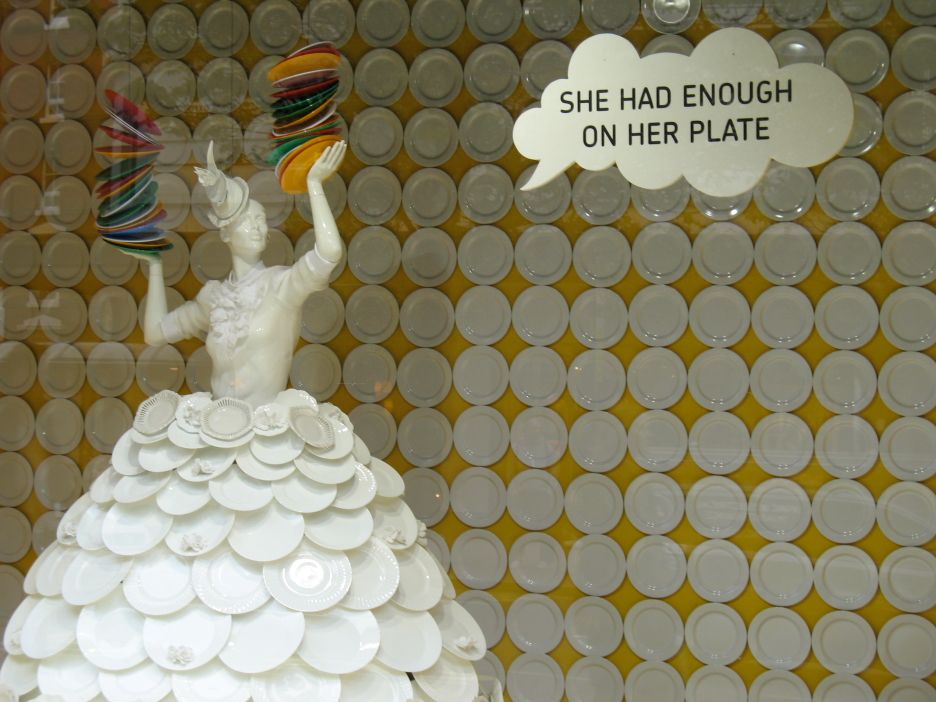 Sculpture of a woman balancing plates, captioned 'She had enough on her plate'